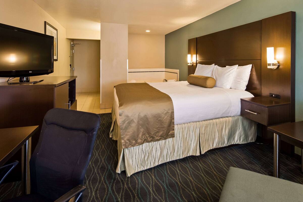 Quarto de hotel com cama, televisão, escrivaninha e cadeira.