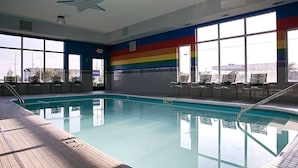 Une piscine intérieure avec de grandes baies vitrées, un plafond décoré de motifs étoilés et un mur aux couleurs de l’arc-en-ciel.