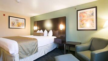 Habitación de hotel con cama, escritorio, silla y dos lámparas de pared.