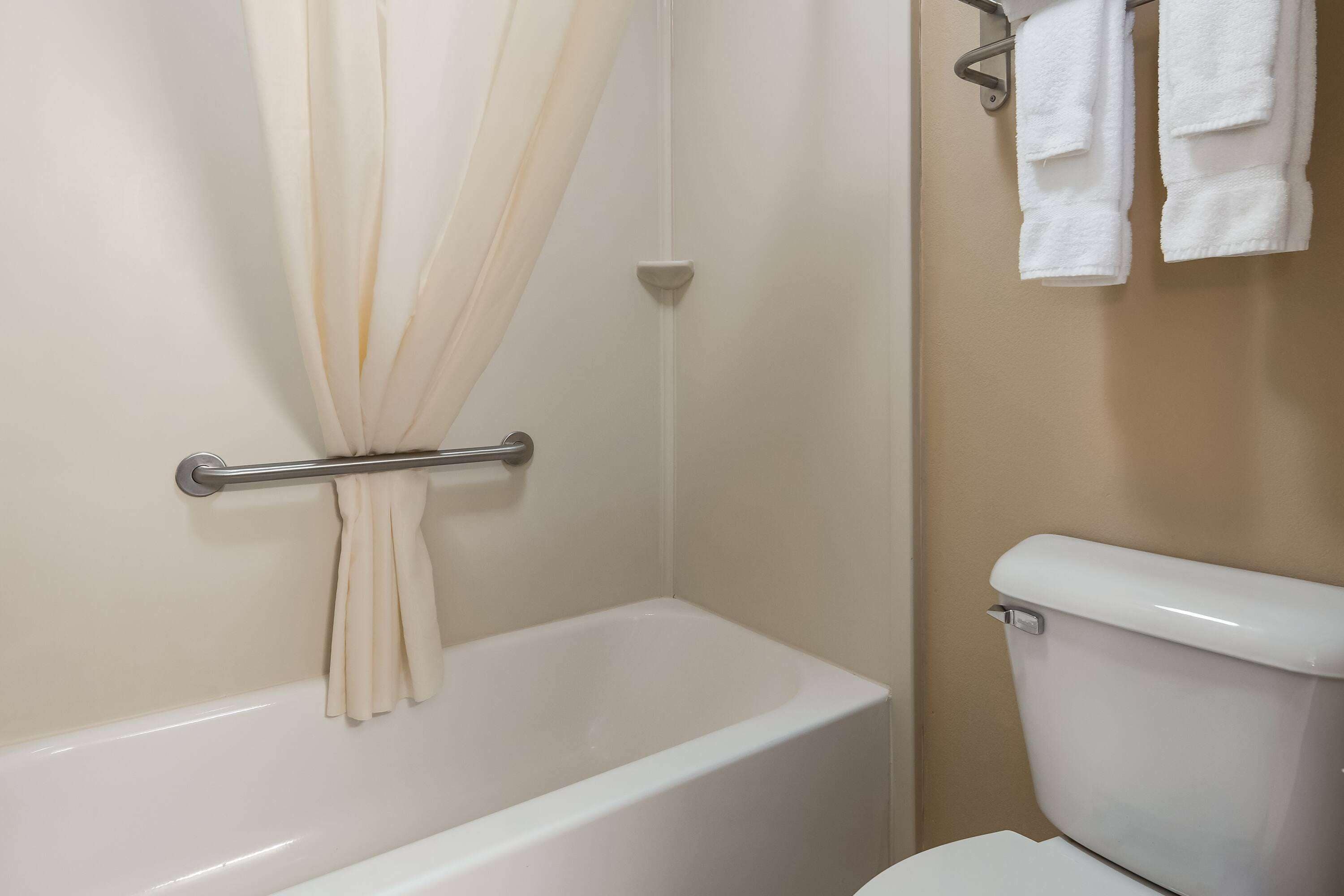 A bathroom with a bathtub, a toilet, and a towel rack with towels.