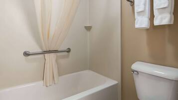 A bathroom with a bathtub, a toilet, and a towel rack with towels.