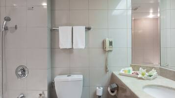A bathroom with a toilet, sink, shower, and a mirror.