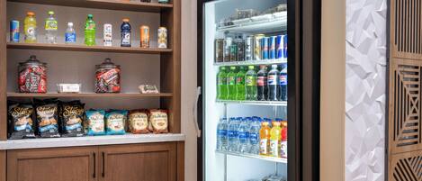 A refrigerated display case stocked with various beverages and snacks, including bottled water, sodas, and packaged foods.