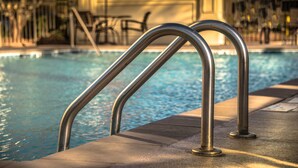 A swimming pool with metal handrails and a concrete edge.