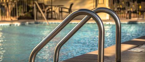 A swimming pool with metal handrails and a concrete edge.
