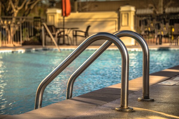 A swimming pool with metal handrails and a concrete edge.