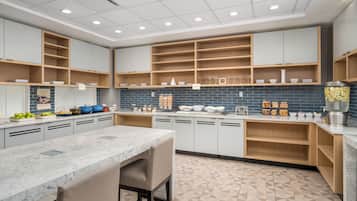 Une cuisine moderne dotée de plans de travail en marbre, d’étagères en bois et d’un revêtement mural en carreaux.