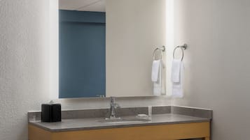 Un baño moderno con lavamanos de mármol, un espejo y un perchero para toallas.