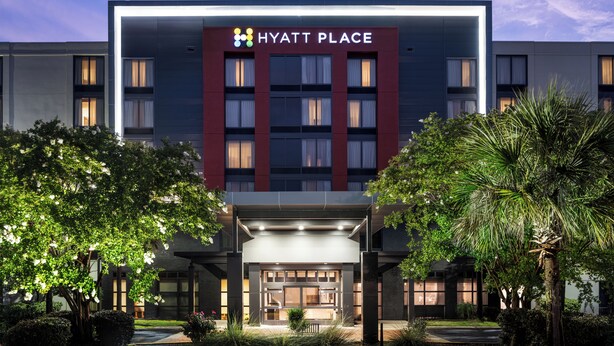 A modern Hyatt Place hotel with a prominent entrance, large windows, and a well-lit facade.