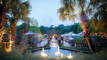 A garden with a central water feature, palm trees, and a gazebo.