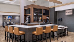 A modern bar area with a central island, bar stools, and a counter with a television.