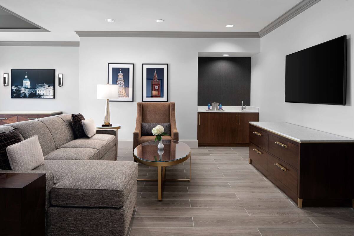 Een moderne woonkamer met een bank, fauteuil, salontafel en kunstwerken aan de muren.