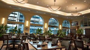 A spacious hotel lobby with large arched windows, modern chandeliers, and comfortable seating areas. - Hilton Indianapolis Hotel & Suites (Indianapolis)