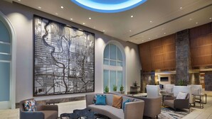 A modern lobby with a large abstract wall art, a curved seating area, and a stone pillar. - Hilton Indianapolis Hotel & Suites (Indianapolis)