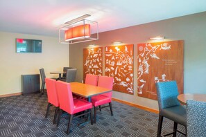 A conference room with a wooden table, red and blue chairs, a patterned carpet, and a wall with white illustrations. - TownePlace Suites by Marriott Portland Hillsboro (Hillsboro)