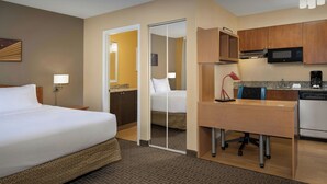 Habitación de hotel con cama, escritorio, kitchenette y baño.