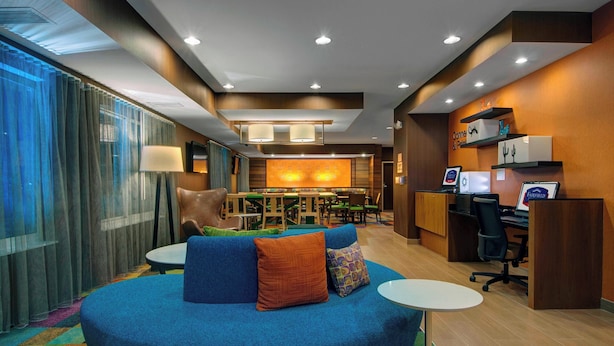 A modern hotel lobby with a blue sofa, a dining area, and a reception desk.