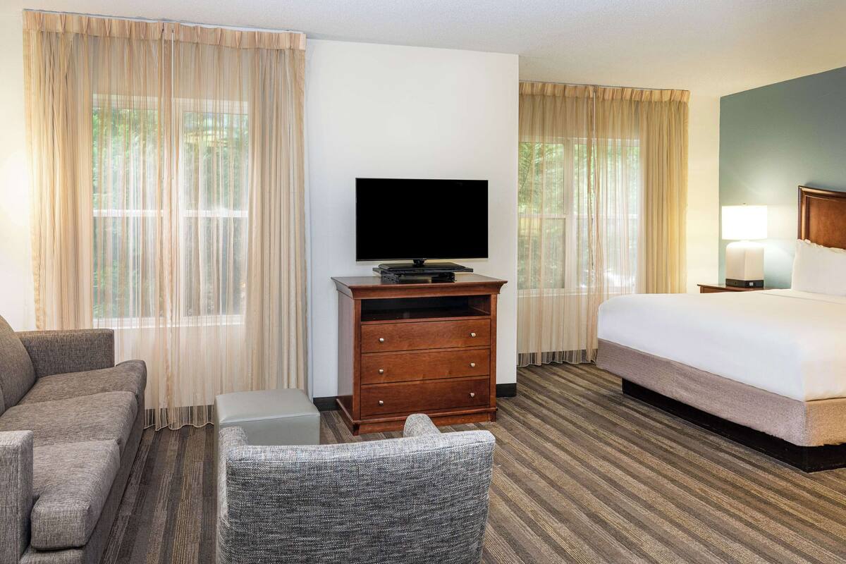 A hotel room with a bed, a TV, a desk, and a chair.