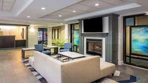 Un hall con zona de estar, chimenea, televisor y máquina expendedora.