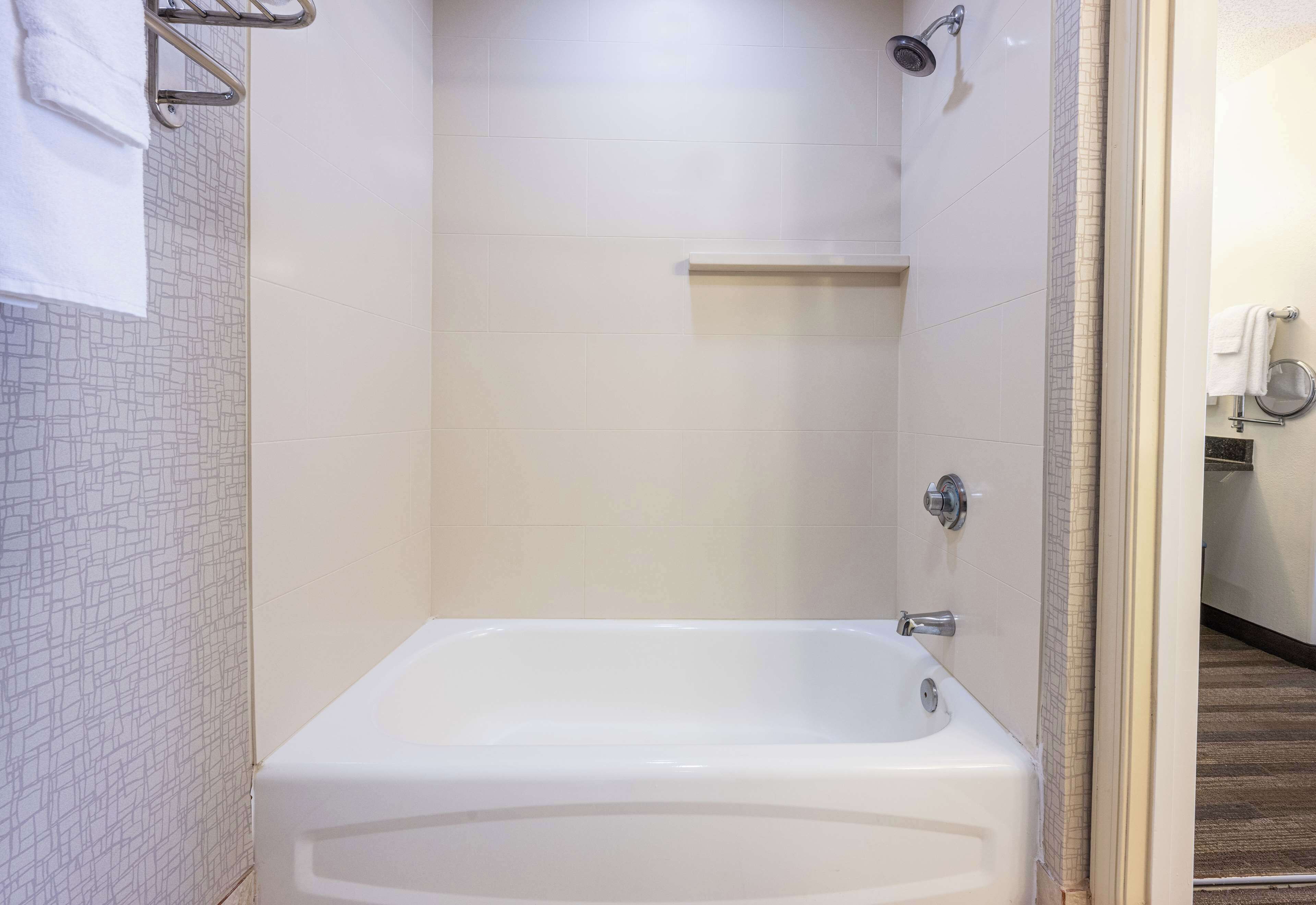Un baño con una bañera blanca, un perchero para toallas y una zona de ducha.