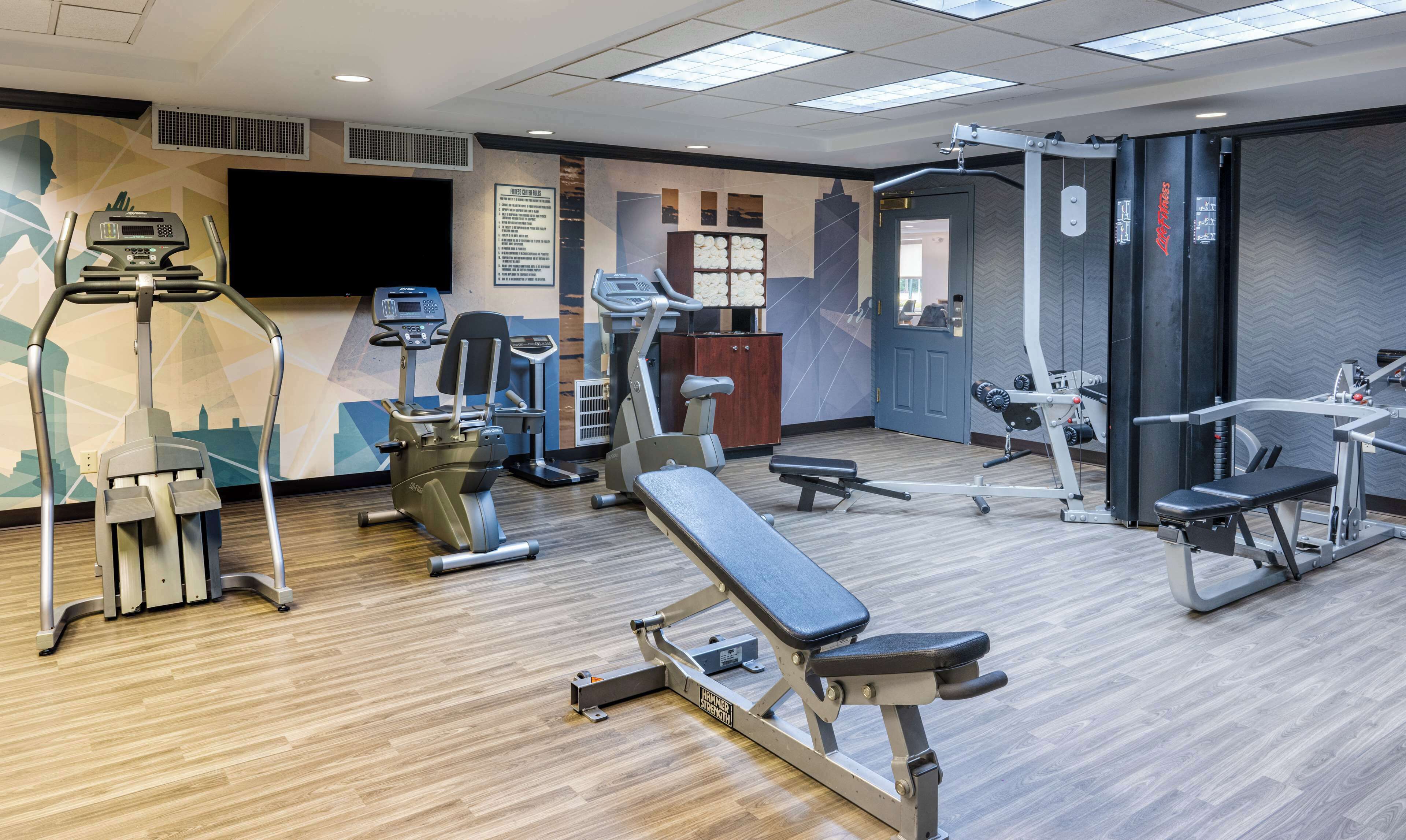 A gym with various exercise equipment, including treadmills, a bench press, and weight machines.