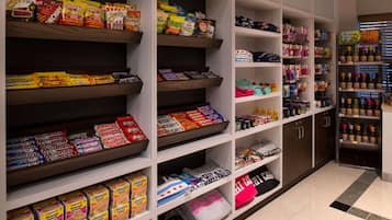 Un espacio comercial bien organizado con estantes llenos de aperitivos, bebidas y ropa.