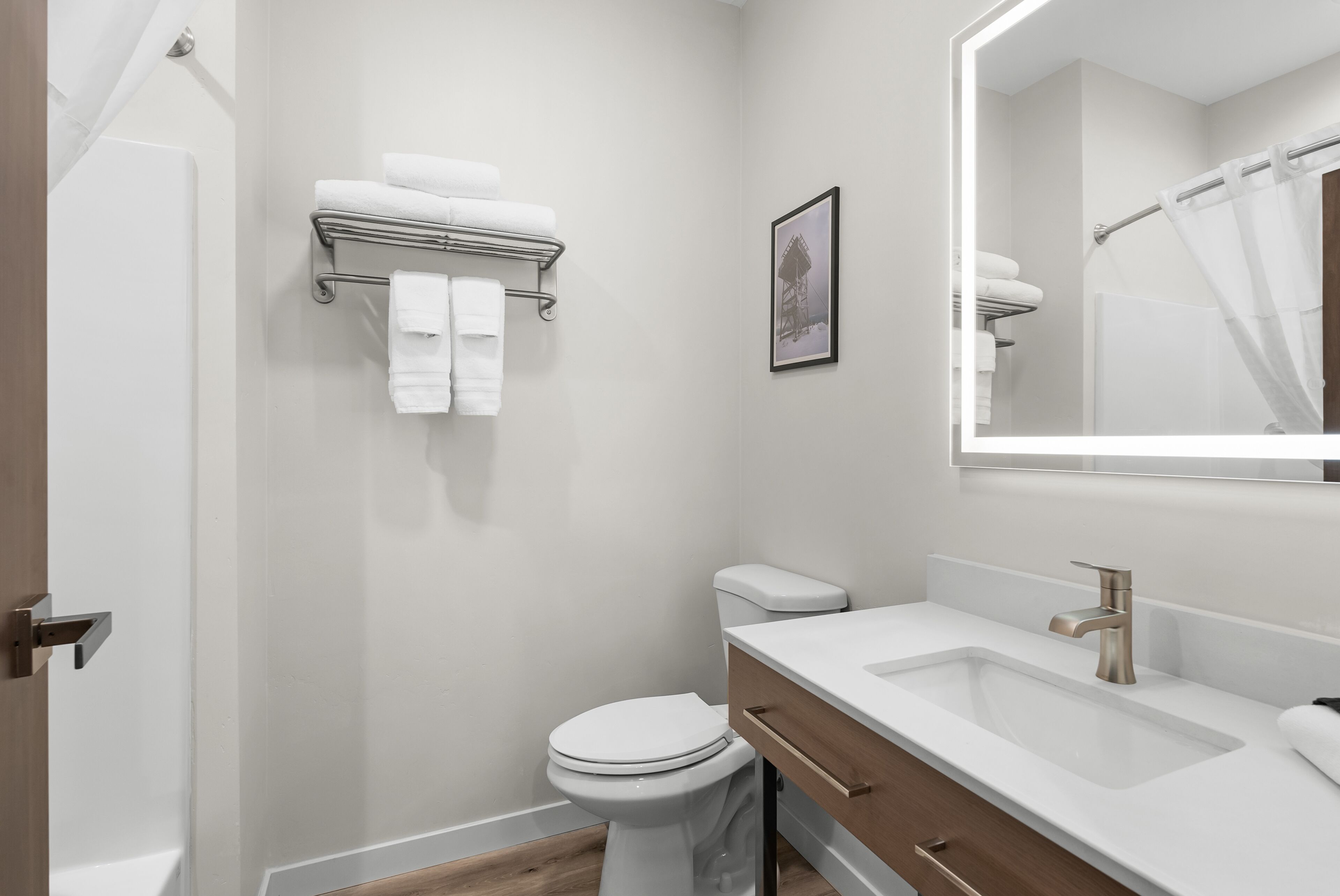 A modern bathroom with a white toilet, a sink with a mirror, and a towel rack.