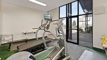 Un gimnasio con cintas de correr, una banca y un amplio ventanal con vistas al exterior.