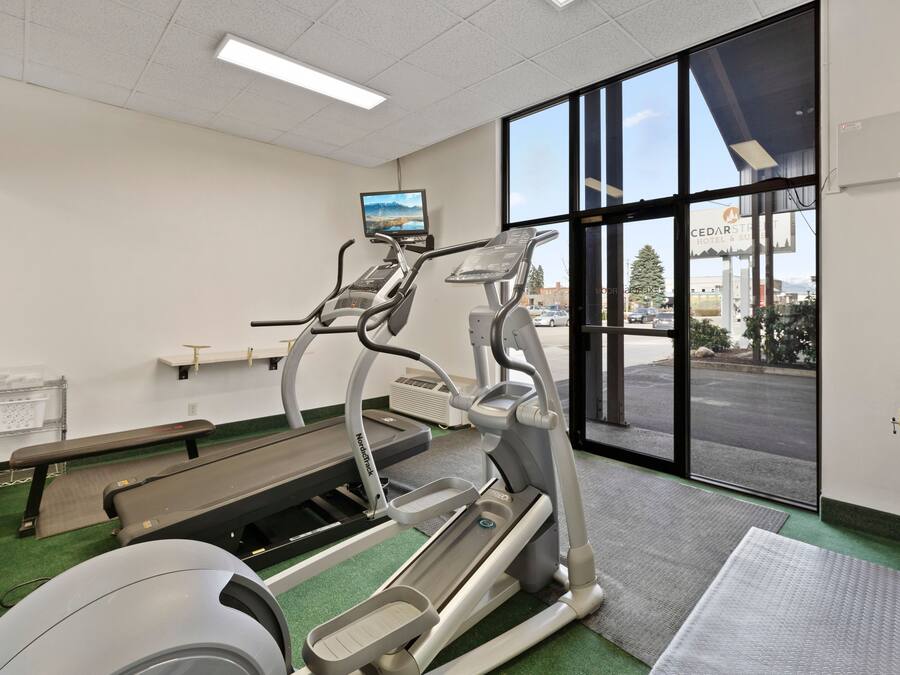 Un gimnasio con cintas de correr, una banca y un amplio ventanal con vistas al exterior.