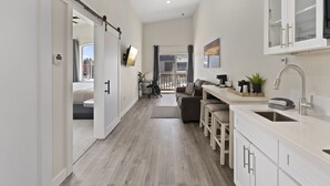 A modern kitchen with a dining area, a sliding door leading to a balcony, and a view of the outdoors. - Sandpoint Hotel & Suites Downtown (Sandpoint)