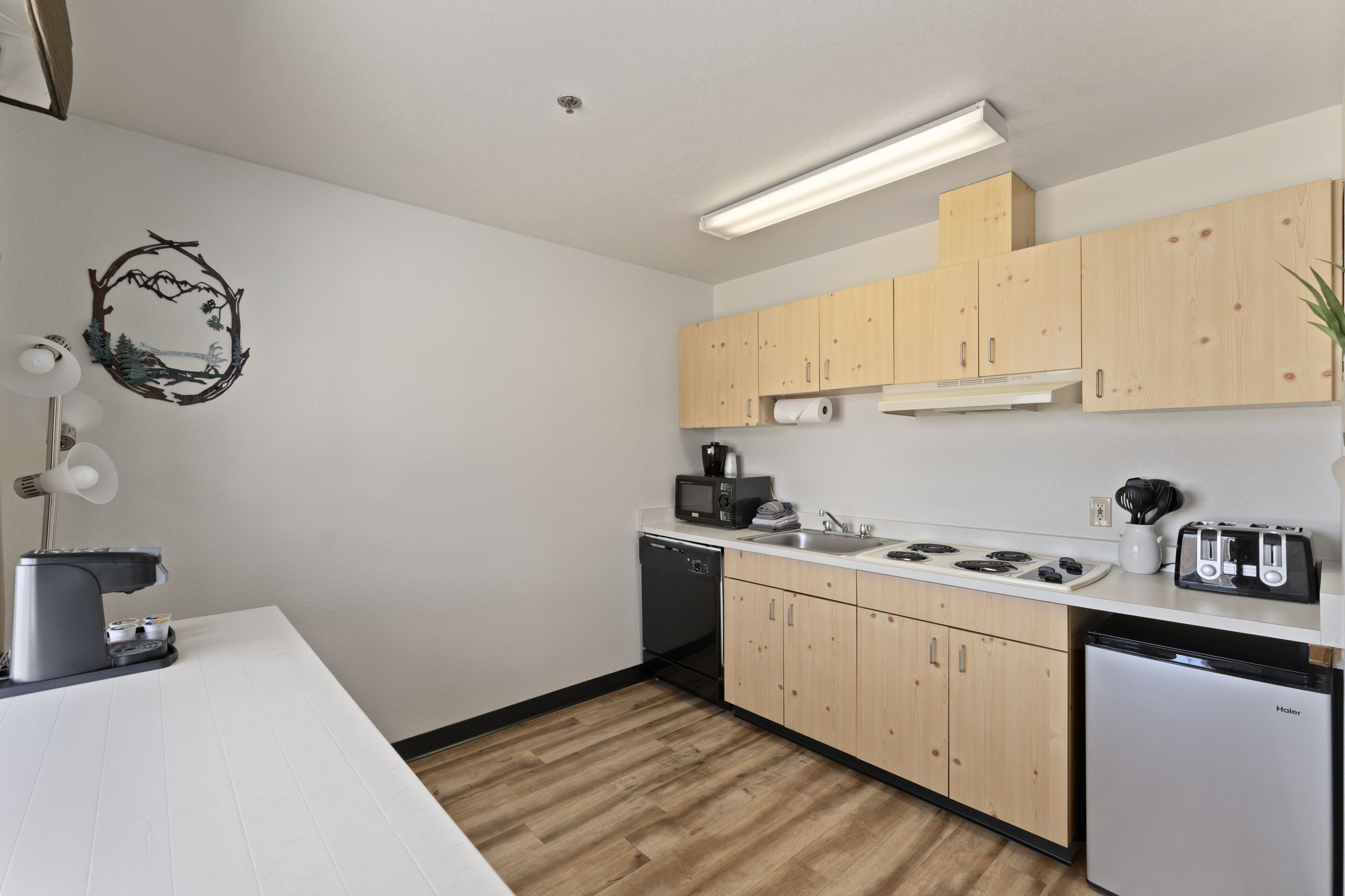 A modern kitchen with wooden cabinets, a built-in stove, a dishwasher, and a countertop with a toaster.