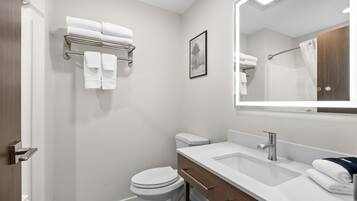 A modern bathroom with a white toilet, a sink with a mirror, and a towel rack with folded towels.