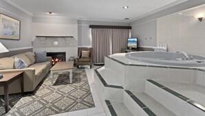 A modern living room with a fireplace, a sofa, a coffee table, and a large bathtub. - Sandpoint Hotel & Suites Downtown (Sandpoint)
