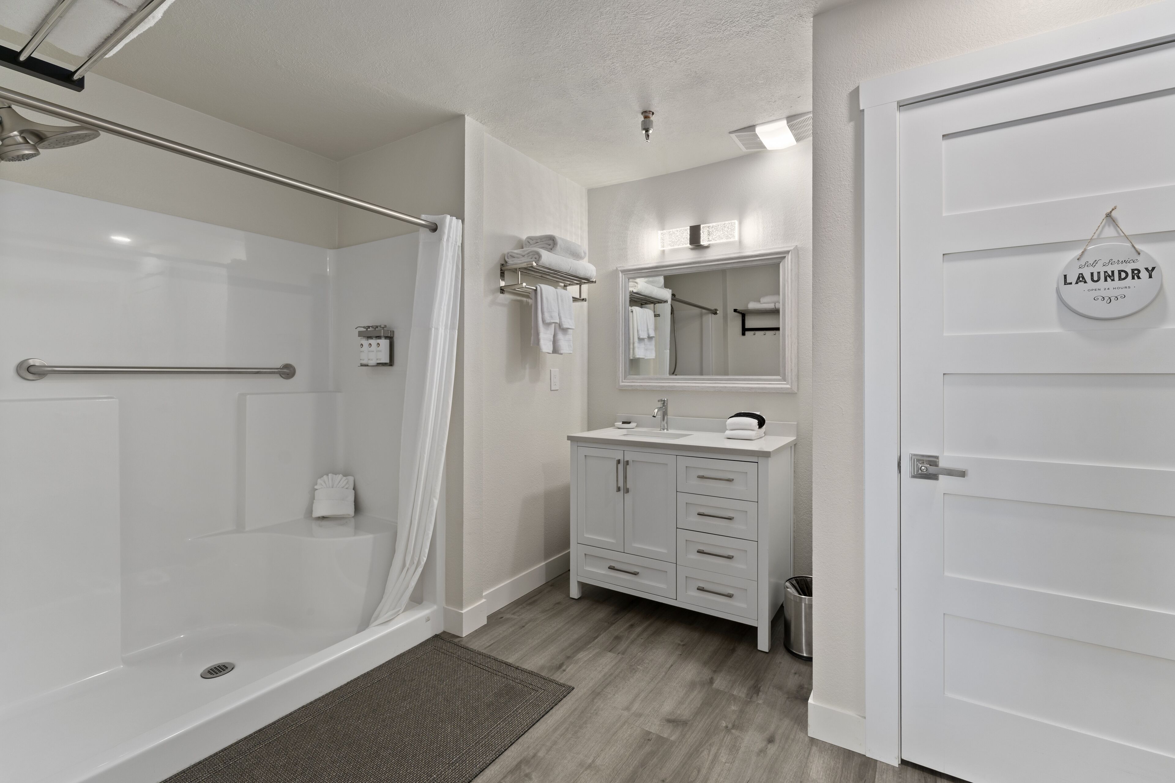 A modern bathroom with a glass shower, white vanity, and a mirror above the sink.
