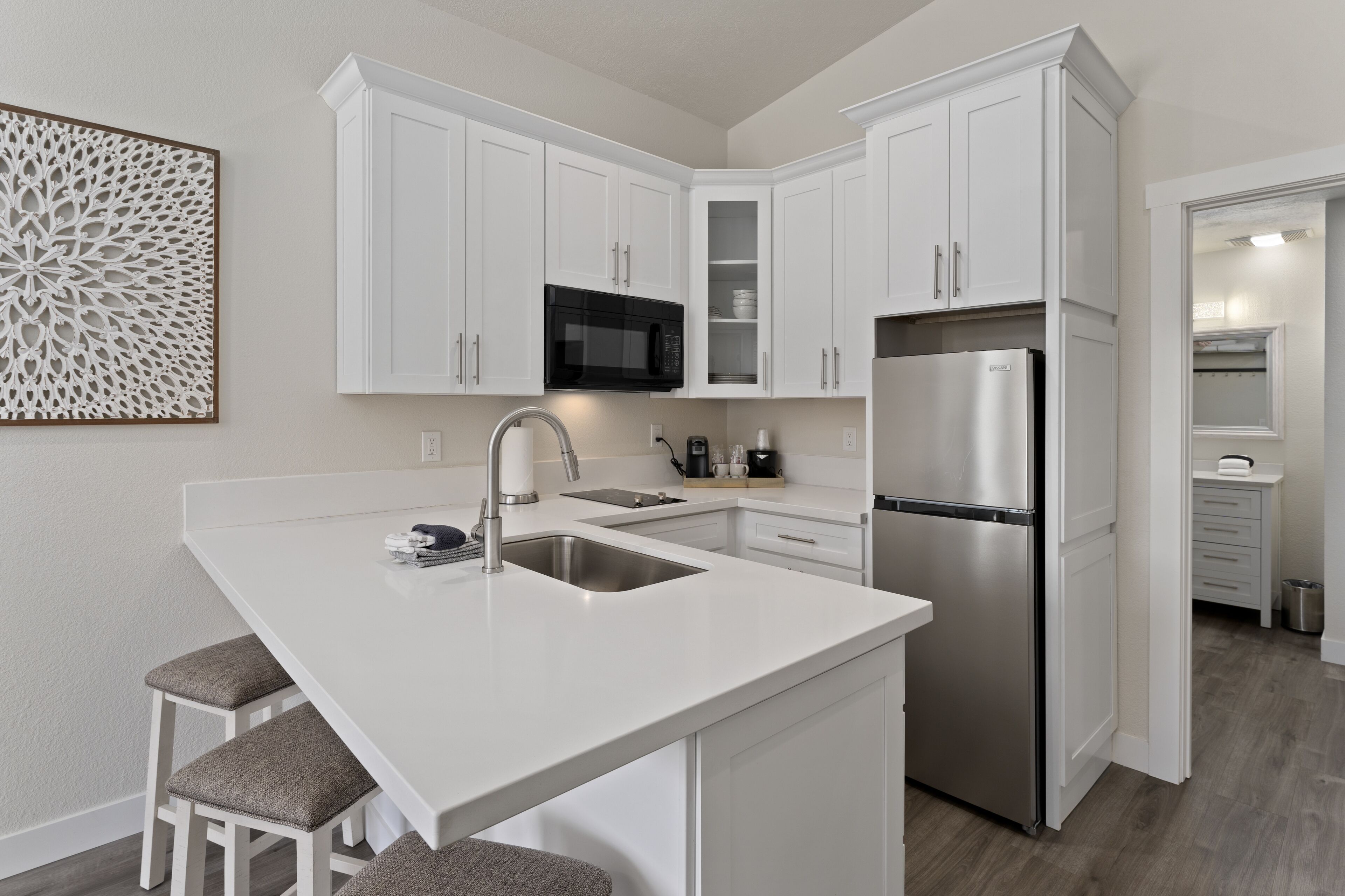 A modern kitchen with white cabinetry, a stainless steel refrigerator, and a built-in microwave.
