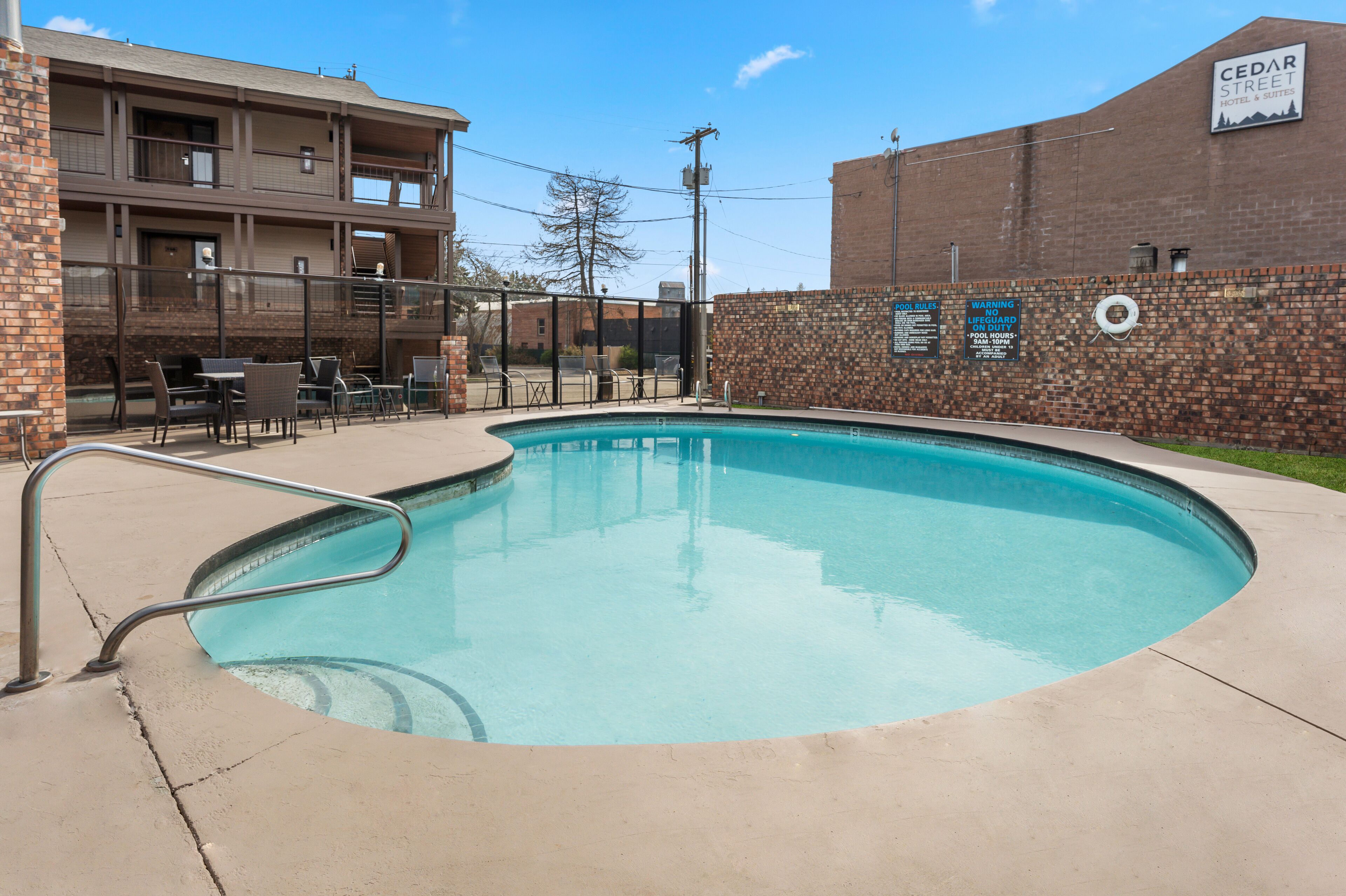 A swimming pool with a brick wall and a Cedar Street Hotel sign.
