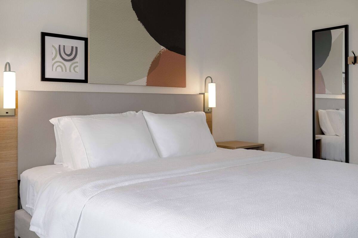 A neatly made bed with white linens in a hotel room.