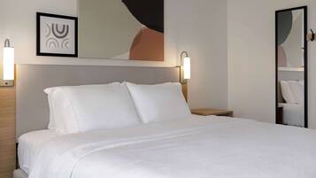 A neatly made bed with white linens in a hotel room.