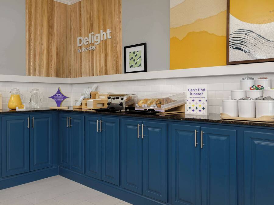 Une cuisine moderne avec des armoires bleues, un mur d’accent en bois et divers appareils de cuisine.