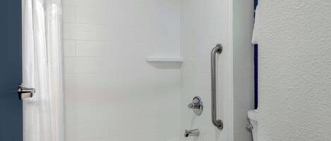 A bathroom with a bathtub, a toilet, and a shower area.