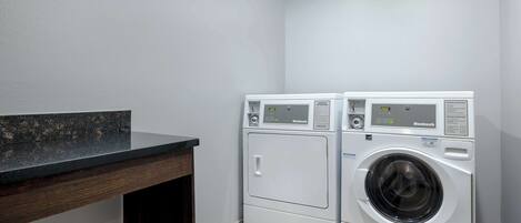 A laundry area with two front-loading washing machines and a dark wooden counter.