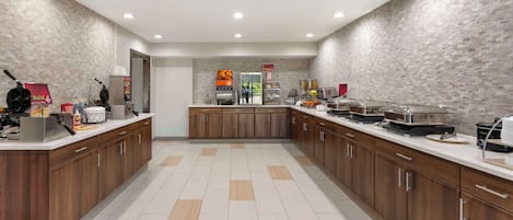 A modern kitchen with wooden cabinets, a central island, and various appliances like a coffee machine and a waffle maker.