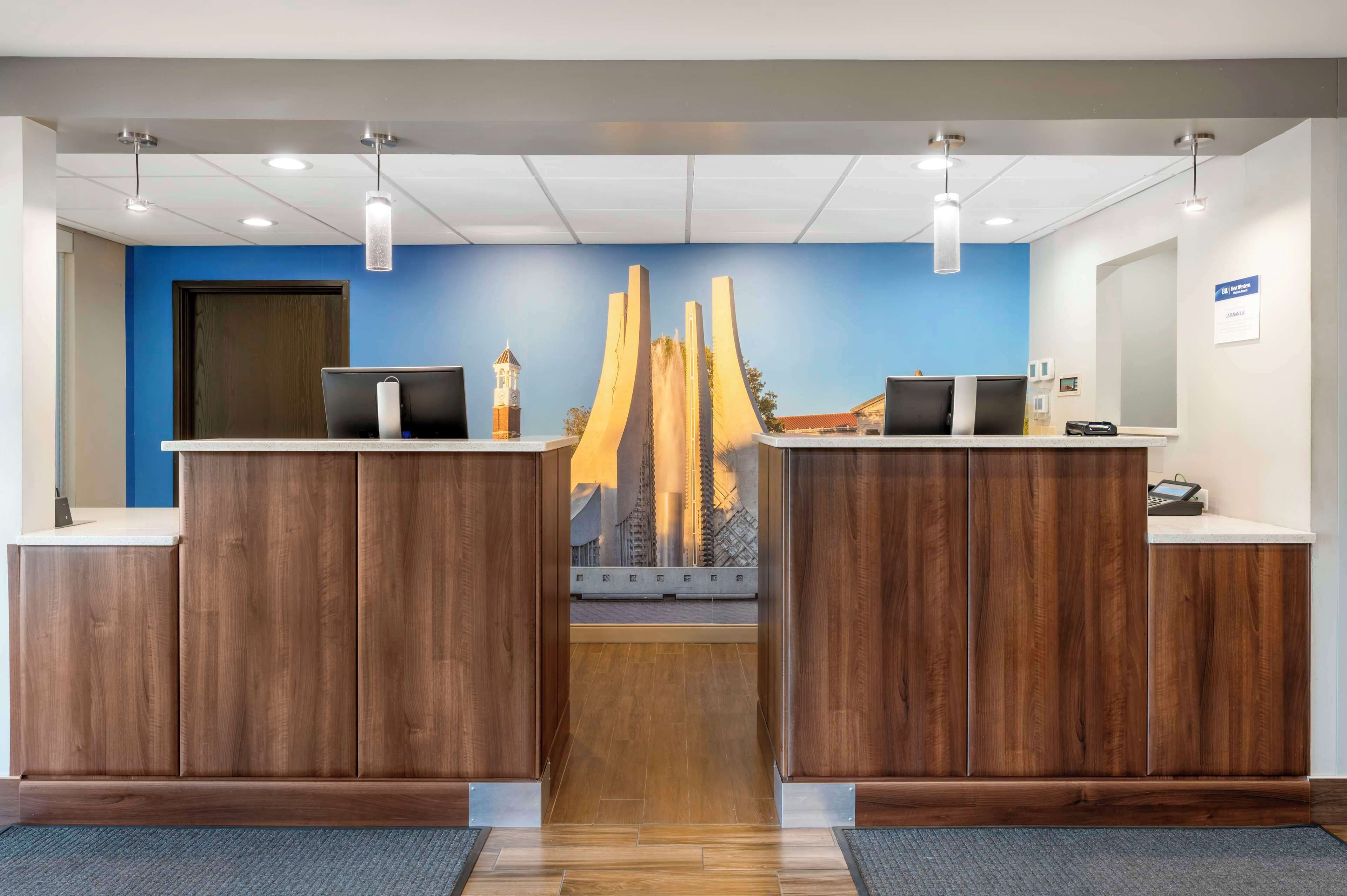 A reception area with two wooden reception desks, a blue wall, and a modern sculpture.