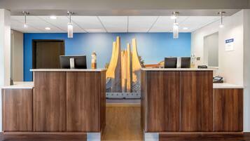 A reception area with two wooden reception desks, a blue wall, and a modern sculpture.