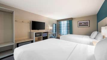 Habitación de hotel con dos camas, televisión, escritorio con silla, ventana con cortinas y un cuadro en la pared.
