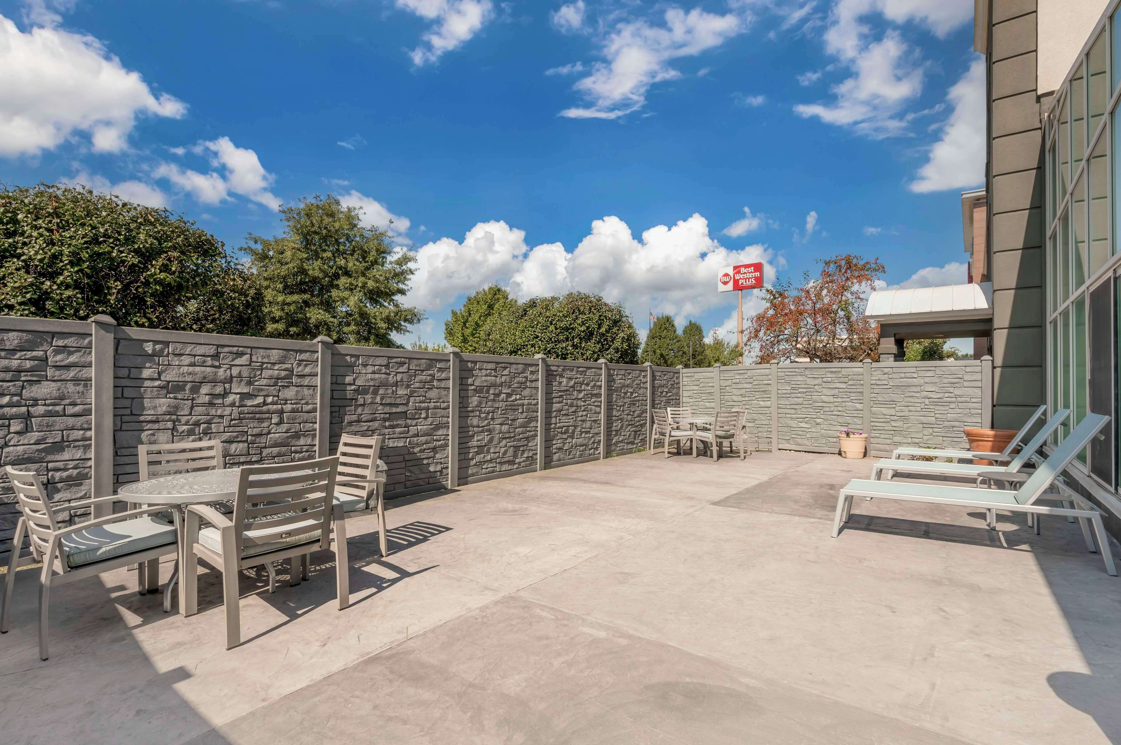An outdoor patio area with stone walls, a table with chairs, and lounge chairs.
