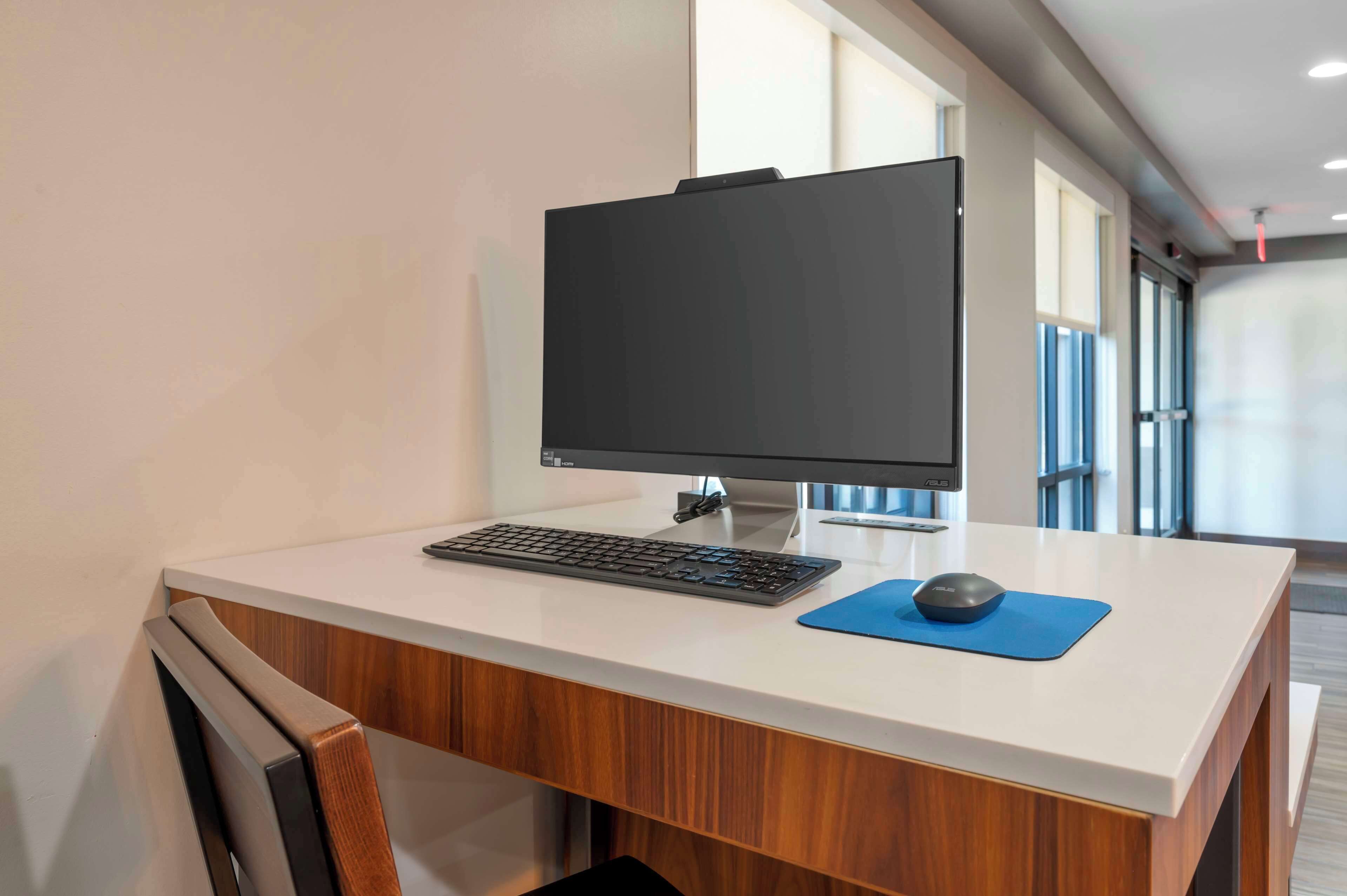 A modern office desk with a computer monitor, keyboard, and mouse.