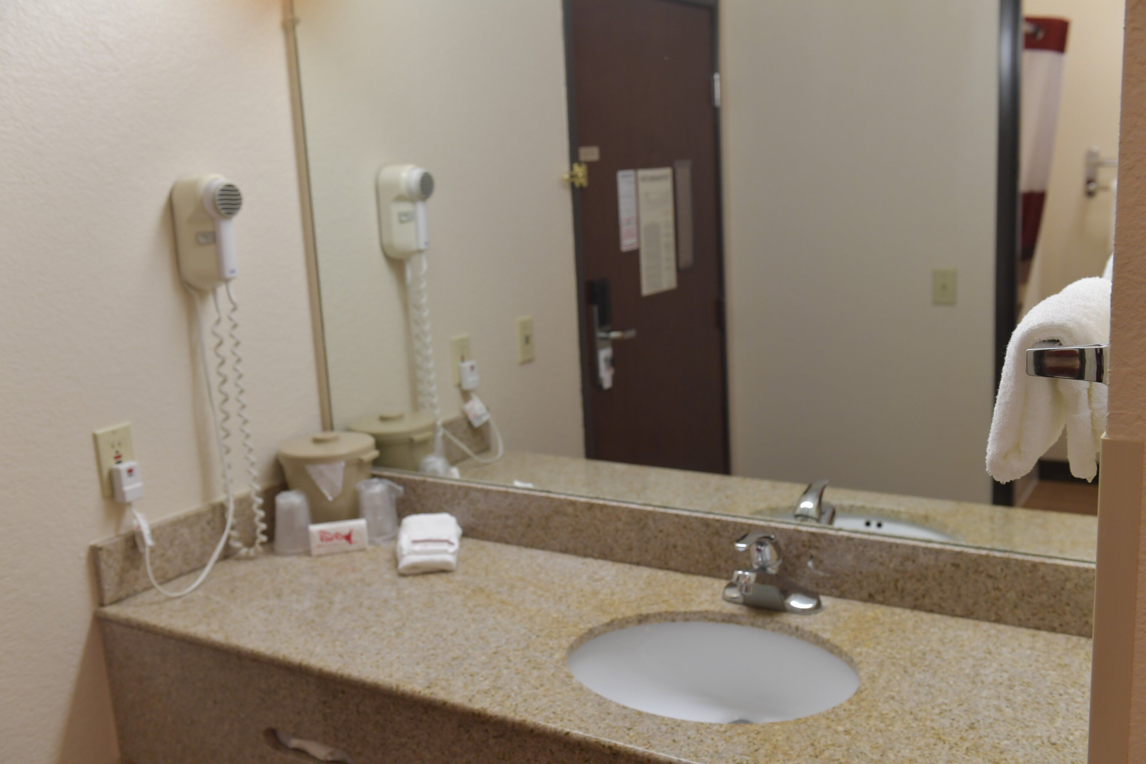 Une salle de bain équipée d’un lavabo, d’un miroir, d’un sèche-cheveux et d’un porte-serviettes.
