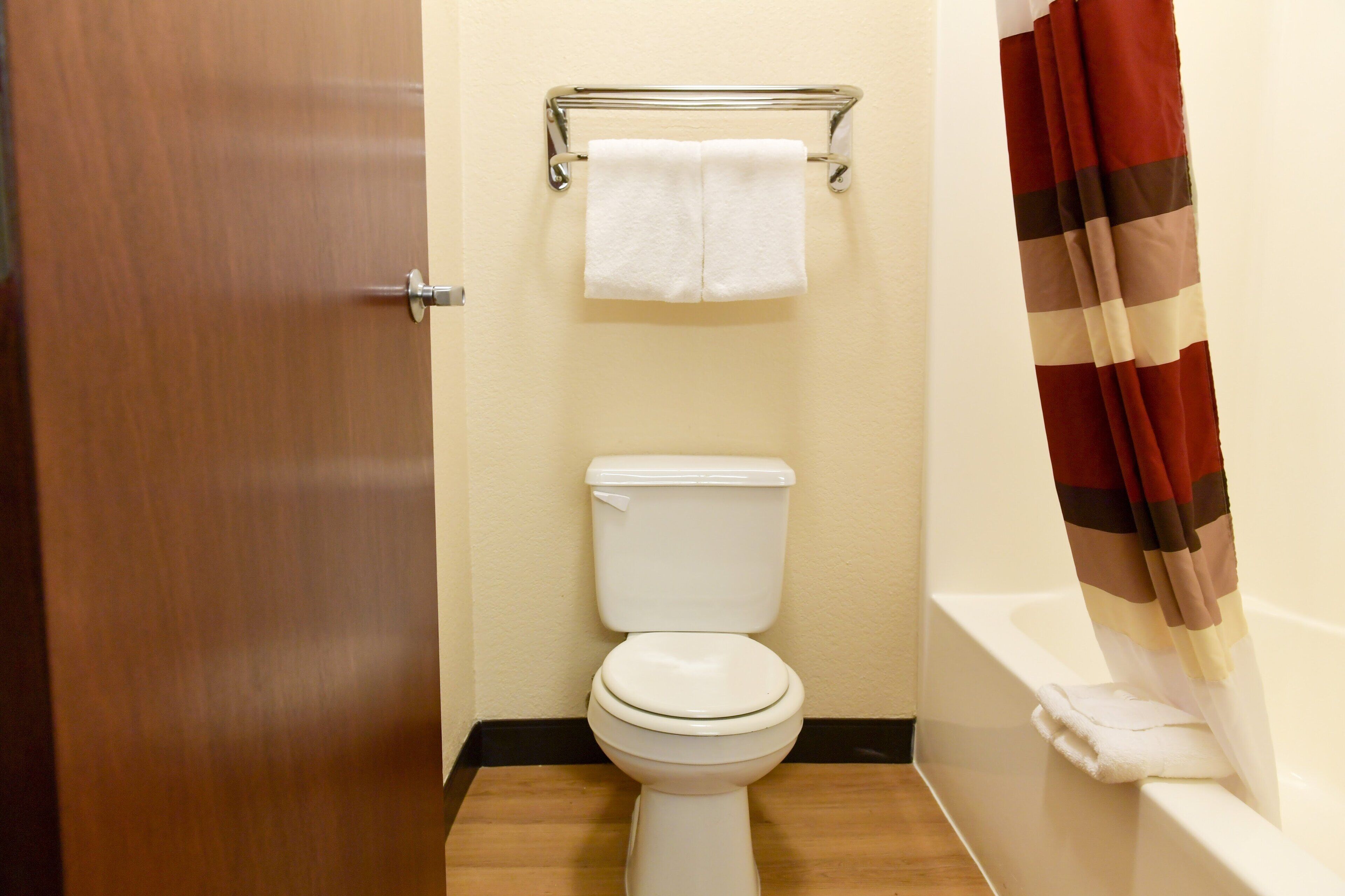 Un baño con inodoro, toallero y cortina de ducha.