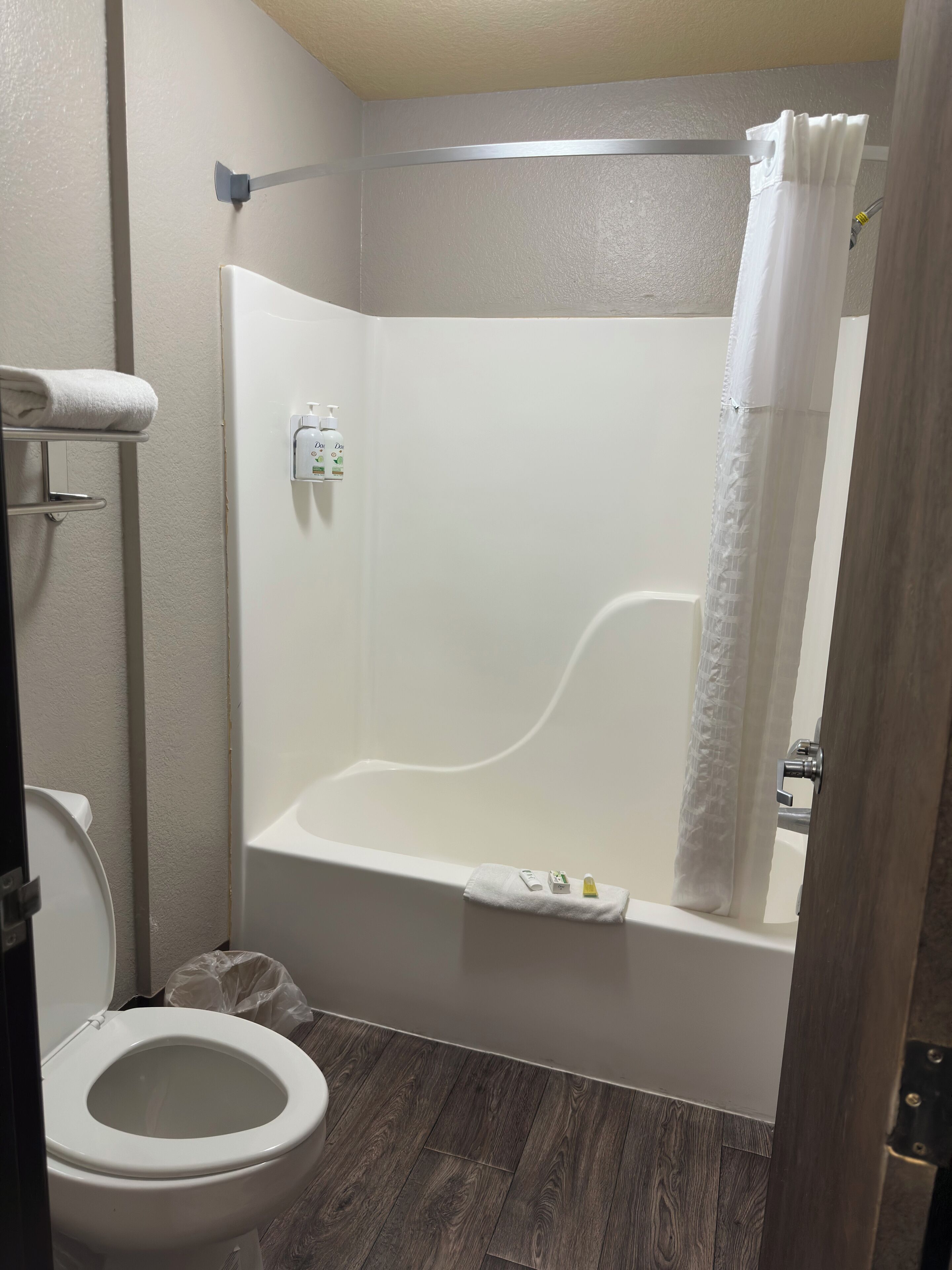 Un baño con una bañera blanca, un inodoro y una cortina de ducha.